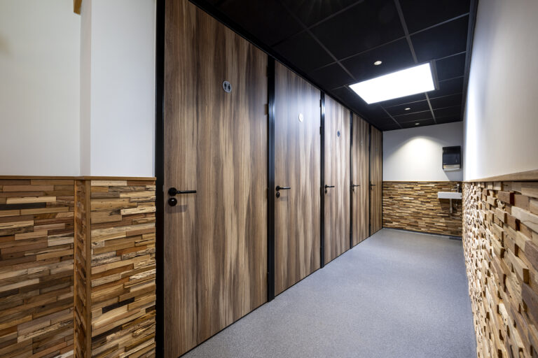 Donkere houtlook cabines naast een wand met houten lambrisering