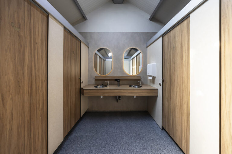 Dubbele wastafel met twee ronde spiegels en houten wandbekleding