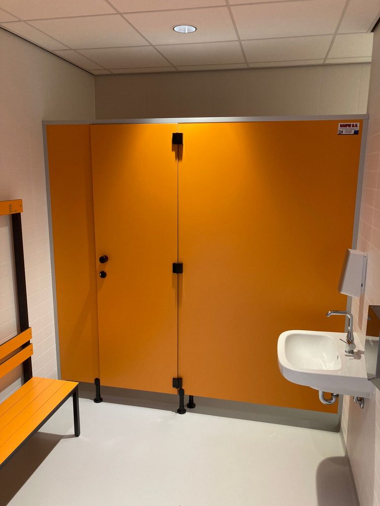 Oranje cabinewand met twee deuren naast een wastafel en bank