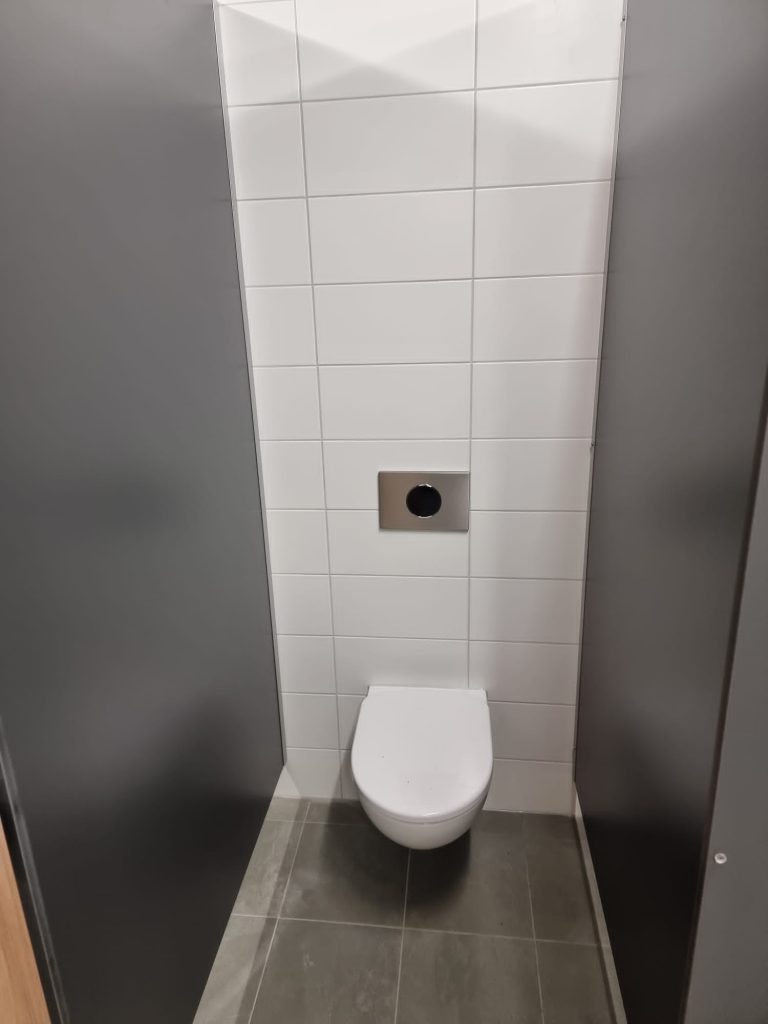Toiletcabine met wit hangtoilet tussen antraciet wanden