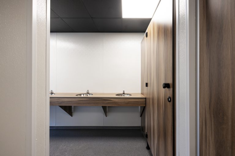 Doorkijk tussen cabines naar een houtlook wastafelblad