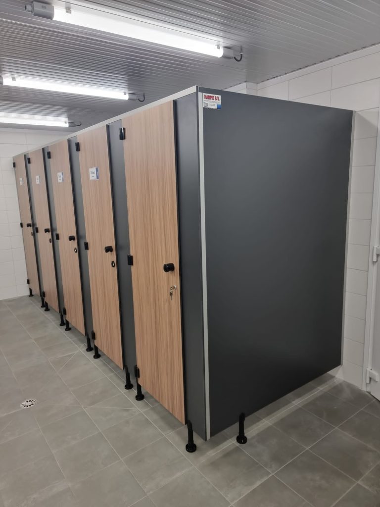 Rij cabines met antraciet en houtlook deuren onder tl-verlichting