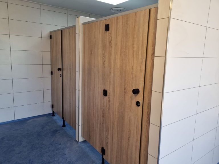Houtlook cabines naast een lichte tegelwand op een blauwe vloer