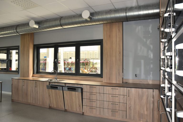 Lang keukenblok in houtlook langs de raamwand van de kantine
