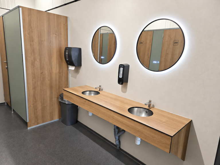 Hoekaanzicht van de wasruimte met een houtlook cabinewand en spiegels